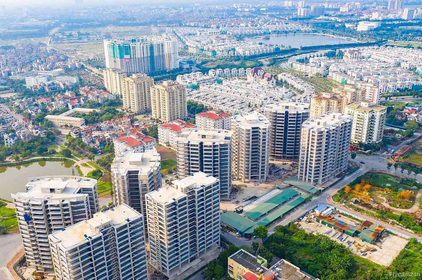 Cụm chung cư cao tầng đang hoàn thiện giữa khu đô thị mới Hà Nội, phía xa là hồ nước và dãy biệt thự, nhìn chéo từ flycam