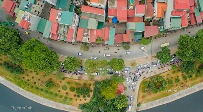 Con đường cong dọc bờ kênh với ô tô đỗ thành hàng và mái nhà nhiều màu, chụp thẳng từ trên xuống