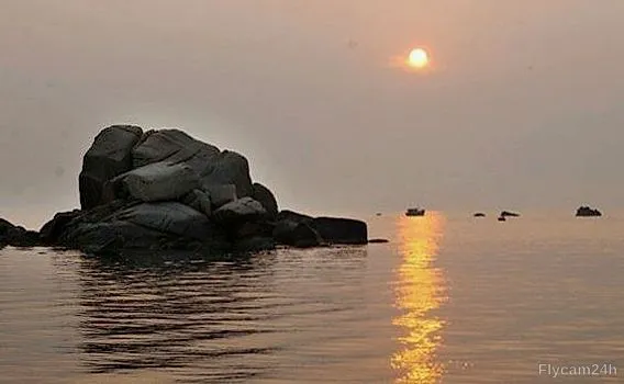 Cụm đá giữa biển lúc hoàng hôn, mặt trời phản chiếu vệt vàng trên mặt nước