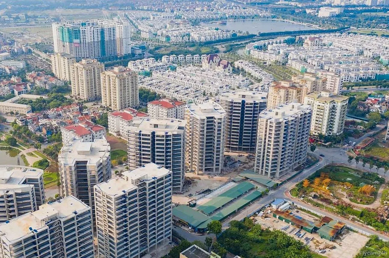 Cụm chung cư cao tầng đang hoàn thiện giữa khu đô thị mới Hà Nội, phía xa là hồ nước và dãy biệt thự, nhìn chéo từ flycam