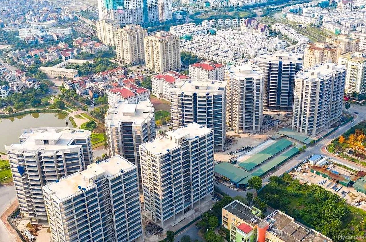 Cụm chung cư cao tầng đang hoàn thiện giữa khu đô thị mới Hà Nội, phía xa là hồ nước và dãy biệt thự, nhìn chéo từ flycam