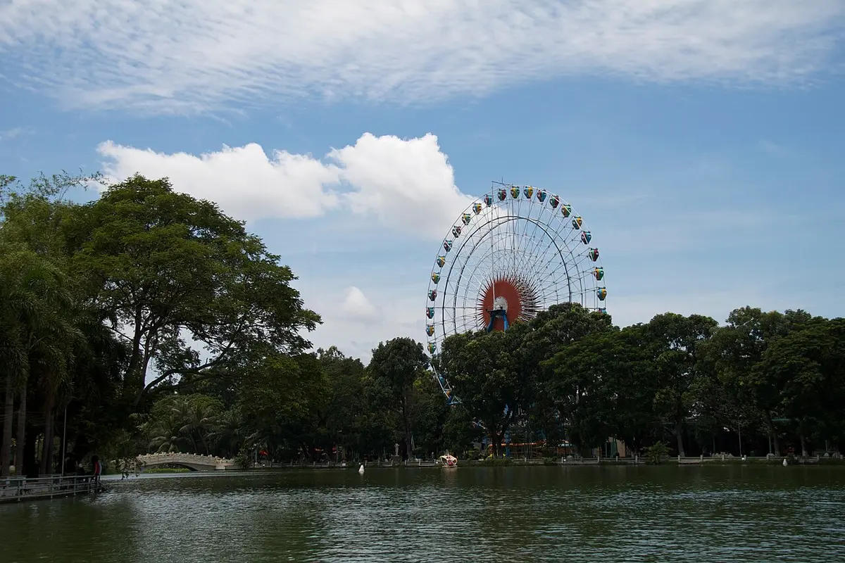 Đu quay nhìn từ bờ hồ và hàng cây trong công viên