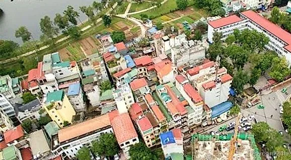 Công trình đang thi công có cẩu tháp giữa khu phố Hà Nội, ven hồ và dãy nhà mái đỏ, nhìn chéo từ flycam