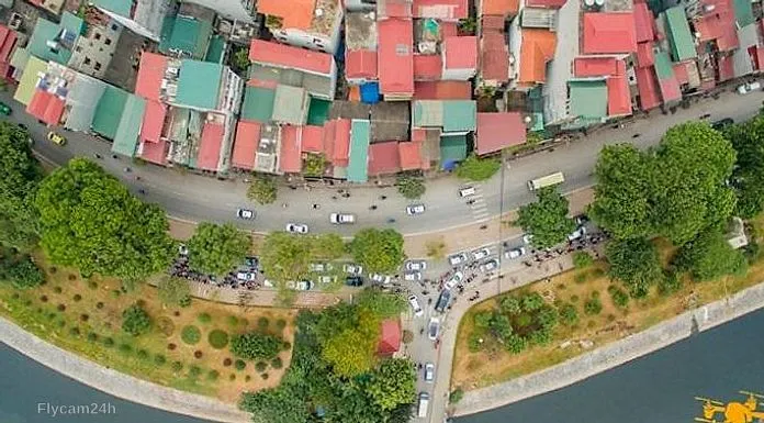 Con đường cong dọc bờ kênh với ô tô đỗ thành hàng và mái nhà nhiều màu, chụp thẳng từ trên xuống