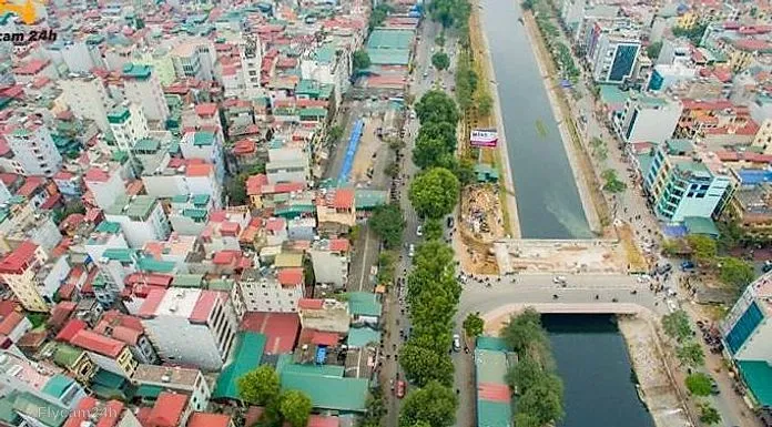 Đoạn kênh trong phố Hà Nội đang thi công cầu và bờ kè, hai bên là đường và dãy nhà, nhìn chéo từ flycam