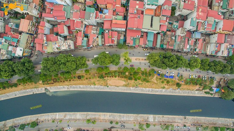 Khu phố Hà Nội nhìn từ trên cao với dòng sông có bờ kè, con đường dọc bờ và dãy nhà mái đỏ
