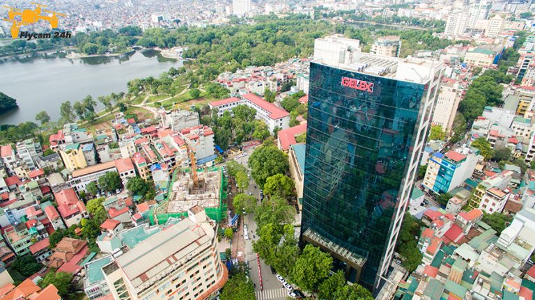 Tòa nhà văn phòng mặt kính cao tầng giữa khu phố thấp tầng Hà Nội, phía sau là hồ nước và mảng cây xanh