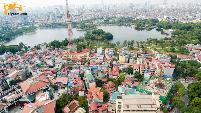 Khu dân cư Hà Nội nhìn từ trên cao có tháp truyền hình, hồ nước và một công trình đang thi công với cẩu tháp